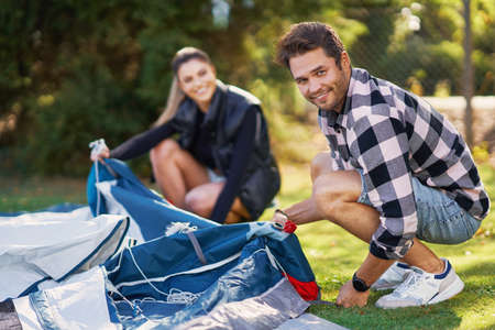 Young nice couple having fun on camping setting up tentの写真素材