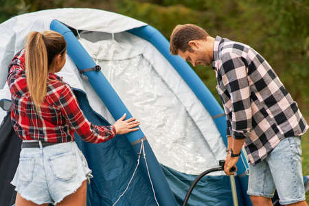Young nice couple having fun on camping setting up tentの写真素材