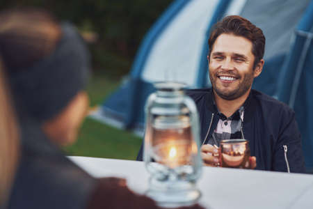 Young nice couple having fun on camping with kerosene lamp