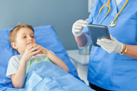 Adult woman and young patient in hospital bedの写真素材