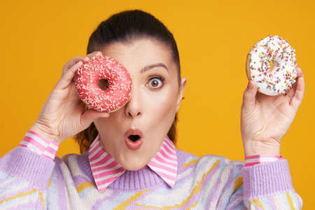 Young beautiful woman over yellow background with donutsの写真素材