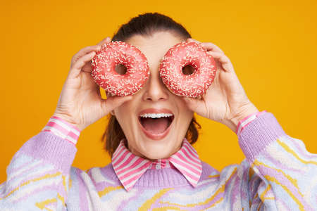 Young beautiful woman over yellow background with donutsの写真素材