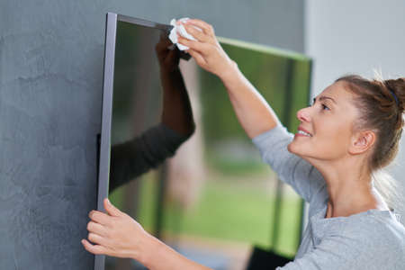 Picture of young woman cleaning tv screenの写真素材