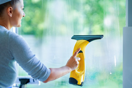 Young woman cleaning window int he kitchen
