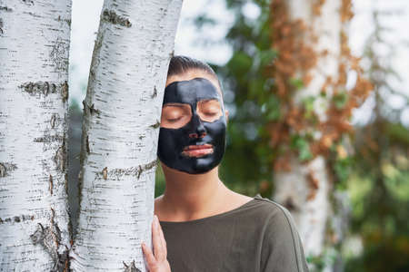 Young woman in nature with black mask on face