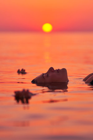 Young woman swimming in the sea on sunrise
