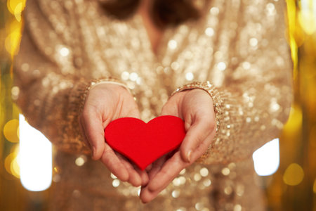 Young woman with heart over gold backgroundの写真素材