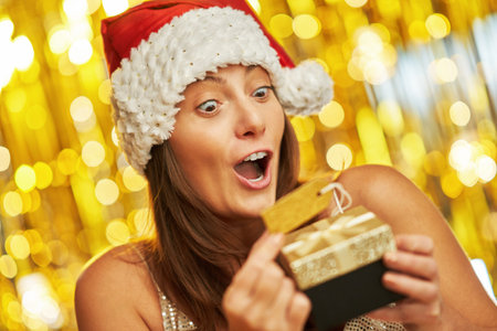 Woman over gold background in Santa Claus hatの写真素材