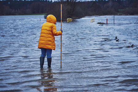 Woman checking water in flood in polish villageの写真素材