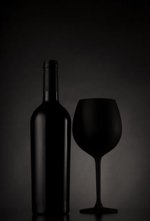 Black wine bottle and black glass of wine on black backgroundの写真素材