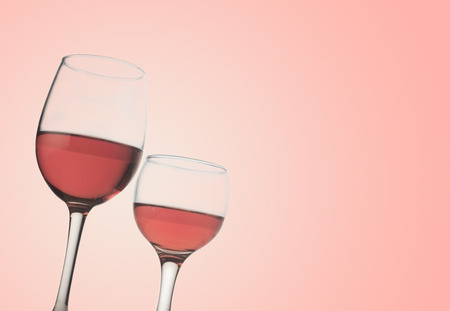 Horizontal front view of two rose wine glasses isolated on pink backgroundの写真素材