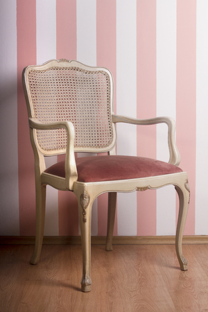 Vintage wooden chair against a pink stripe interior wallの写真素材