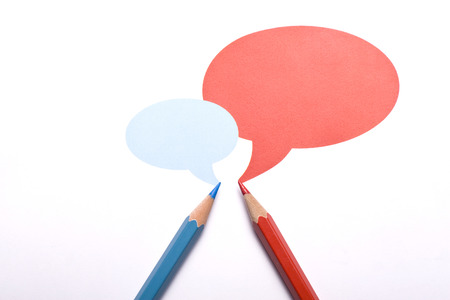 Horizontal top view of a red and a blue pencil with speech bubbles of different sizes above them isolated on white background.の写真素材