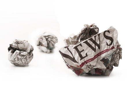 Horizontal front view of a ball of twisted newspaper page with the word news visible isolated on white backgroundの写真素材