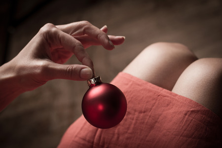 Woman with red dress holding a red Christmas globe with her fingersの写真素材
