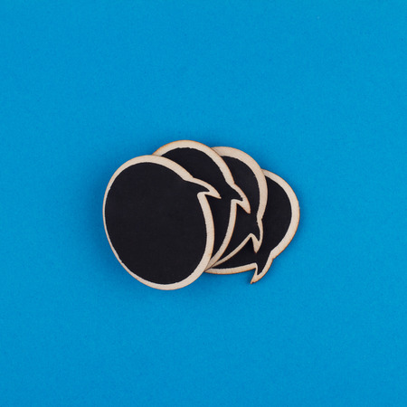 top view of black wooden speech bubbles on top of each other on blue background