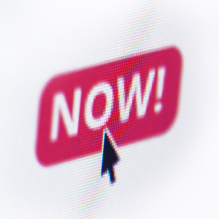 close up of computer screen with red button the text now and a mouse cursor over