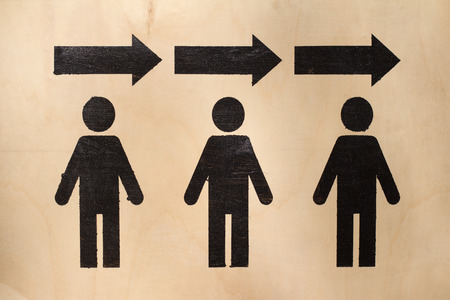 exit symbol with three human black icons with arrows above them on wood texture 