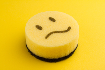 dish washing concept yellow sponge with sad scared faceの写真素材