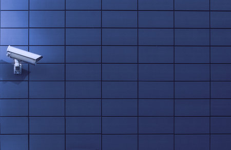 Horizontal front view of a surveillance monitoring white camera viewed from a side with blue...