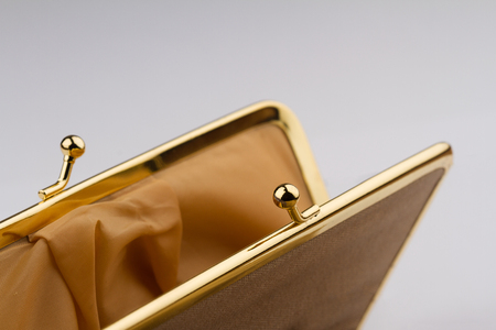 macro detail of open female cream colored vintage wallet with golden metal enclosure on grey backgroundの写真素材