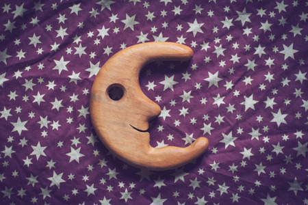 top view concept wrinkled background texture of purple textile table cloth with white stars and wooden toy moon smiling in the centerの写真素材