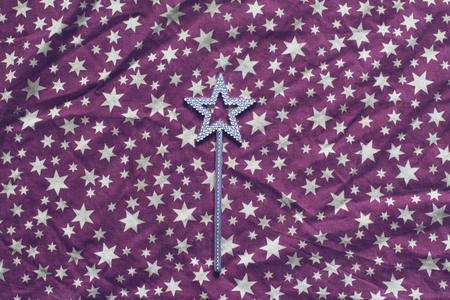 top view of wrinkled background texture of purple textile table cloth with white stars and silver magic wand in the centerの写真素材