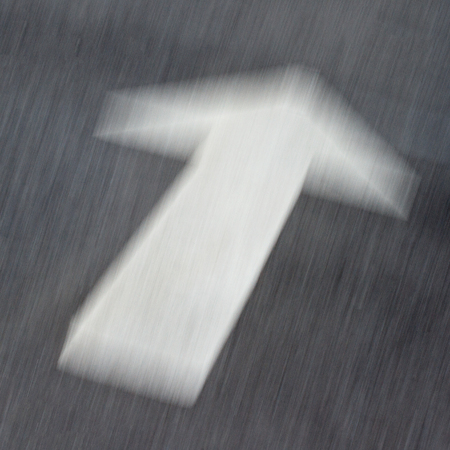 close up of motion blur white arrow on asphalt black roadの写真素材