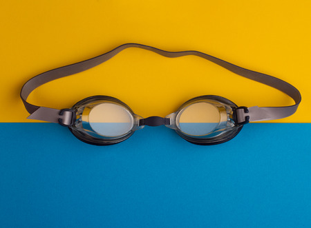 top view of swimming goggles on blue and yellow background paperの写真素材