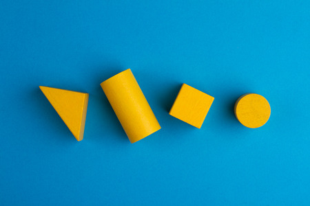 abstract color composition with yellow wood toy building blocks on blue paper backgroundの写真素材