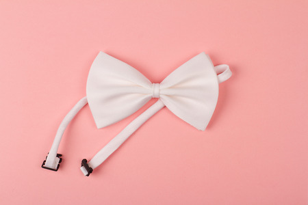 white bow tie with textile band on light pink backgroundの写真素材