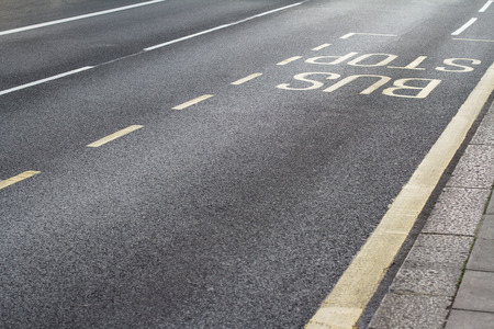 perspective view of bus stop words written on the street asphalt next to a sidewalkの写真素材