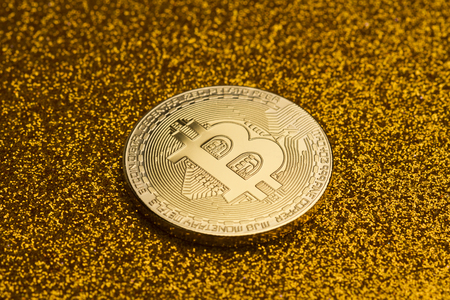 horizontal top view of single bitcoin coin on golden glittering background texture concept for richの写真素材