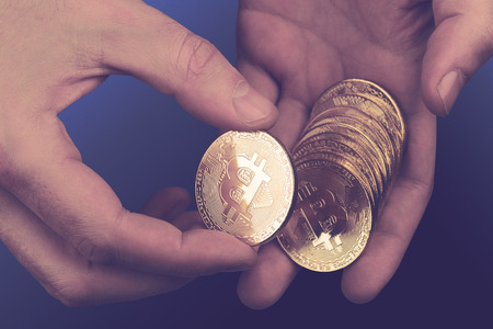 cryptocurrency concept with closeup of Caucasian hands counting a pile of bitcoin golden coinsの写真素材