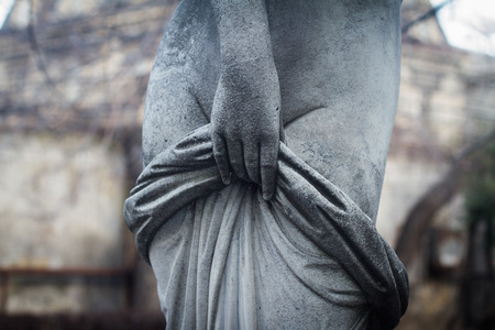 front view detail closeup of old woman stone sculpture statue with hand covering naked body with...