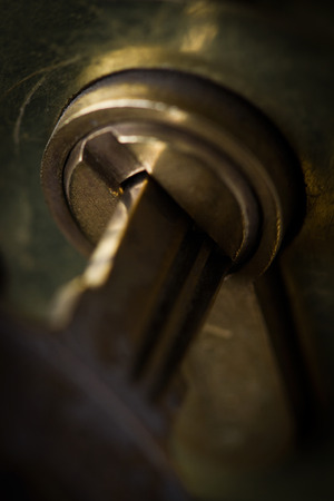 Vertical macro closeup with selective focus of metallic key opening a metal cylinder lockの写真素材