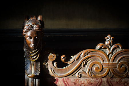Front view closeup detail of antique wooden young woman figurine sculpture with closed eyes in natural lightning on dark backgroundの写真素材