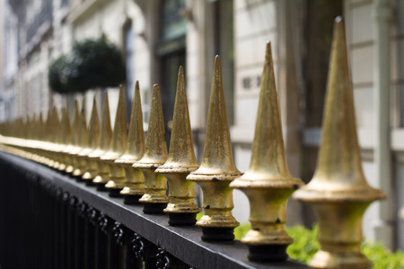 perspective horizontal view of golden painted iron fence spikes surrounding a residential propertyの写真素材