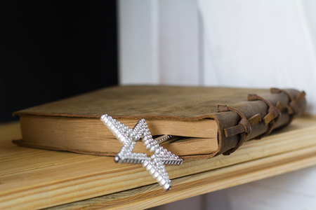 perspective view of vintage closed book with leather brown binding and a silver star magic toy wand insideの写真素材