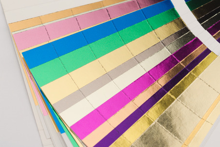 front view close up of multicolor color stamping hotfoil paper spectrum sampler isolated on white backgroundの写真素材