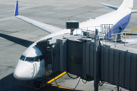horizontal front view closeup of passenger plane with embarkation tunnel ready for take off on airport runwayの写真素材