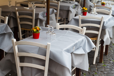 perspective view closeup of traditional Italian street  restaurant terrace with white tables and chairs on old sidewalkの写真素材