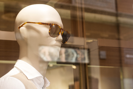 side view closeup of white plastic male mannequin wearing sun glasses in clothing store window displayの写真素材