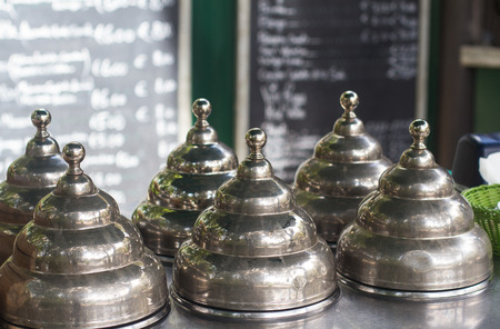 front view closeup of metallic chrome icecream vintage retro lid covers on the terrace of a street...