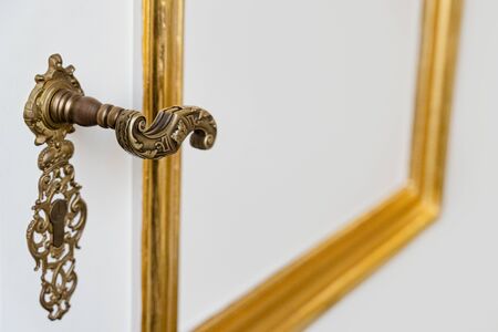 side view detail of vintage antique golden door knob with metallic carvings and keyhole on white...