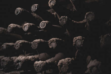perspective view closeup of stacked aged wine bottles ancient collection covered with soft black mold and spiderweb in vintage wine cellarの写真素材
