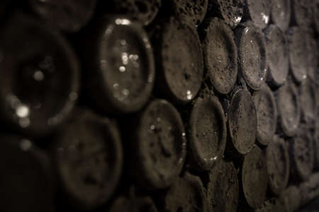 front view closeup of stacked aged wine bottles ancient collection covered with soft black mold and spiderweb in vintage wine cellarの写真素材