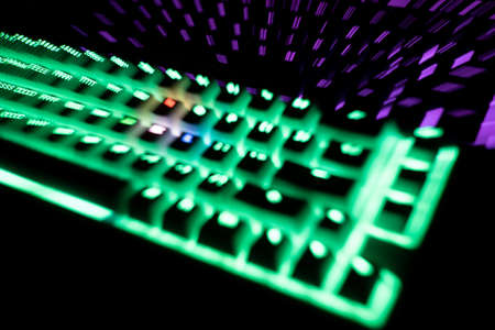 out of focus top view detail closeup of two illuminated mechanical gaming RGB keyboard with keycaps lighting up in different colors in the darkの写真素材