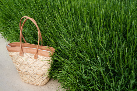 front view closeup of empty brown wicker bag with green grass in the backgroundの写真素材