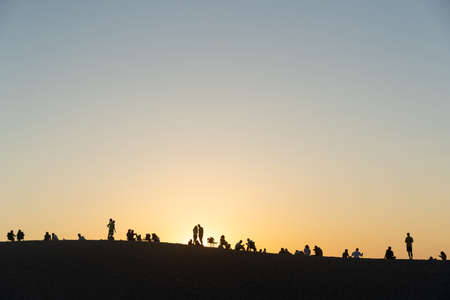 GELEMIS, TURKEY - JULY 7, 2021: Silhouettes of local people and tourists who gather at sunset in the...